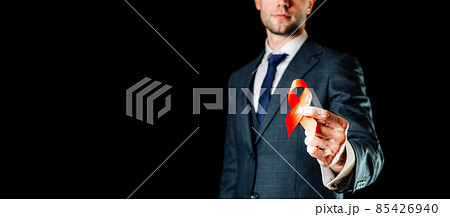 Hiv aids. Red ribbon in hiv world day isolated on dark background. Man holding awareness aids and cancer symbol. Health, Medical sign. copy space. Hiv aids. Red ribbon in hiv world day isolated on dark background. Man holding awareness aids and cancer symbol. Health, Medical sign. copy space. 85426940