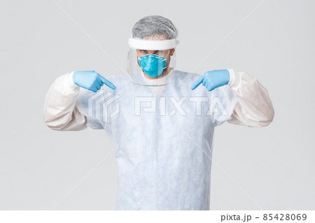 Covid-19, pandemic, healthcare workers fighting virus outbreak. Confident young doctor in medical mask, rubber gloves and personal protective equipment pointing at himself, saving lives of patients Covid-19, pandemic, healthcare workers fighting virus outbreak. Confident young doctor in medical mask, rubber gloves and personal protective equipment pointing at himself, saving lives of patients 85428069