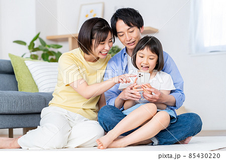 リビングでスマホを見る若い家族 リビングでスマホを見る若い家族 85430220