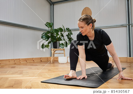 barefoot woman practicing yoga stretches on mat in indoors studio barefoot woman practicing yoga stretches on mat in indoors studio 85430567