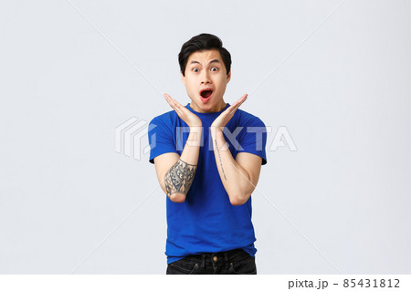 Excited and shocked young asian guy, speechless man drop jaw, gasping as find out news, being amazed with awesome promo or special discount, standing in blue t-shirt over grey background 85431812