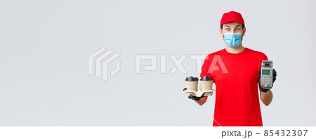 Takeaway, food and groceries delivery, covid-19 contactless orders concept. Excited and surprised client or employee in red uniform, face mask and gloves, giving client paying terminal with coffee 85432307