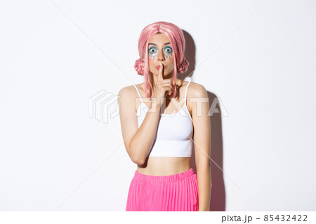 Worried attractive girl in pink anime hair and glitter, asking keep quiet, showing shush sign, press index finger to lips and looking concerned. Woman share a secret, standing over white background Worried attractive girl in pink anime hair and glitter, asking keep quiet, showing shush sign, press index finger to lips and looking concerned. Woman share a secret, standing over white background 85432422