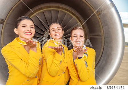 Joyful women stewardesses standing near aircraft engine Joyful women stewardesses standing near aircraft engine 85434171