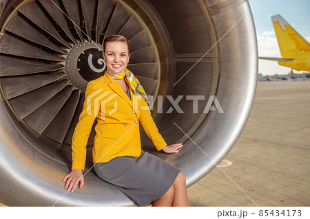 Joyful woman stewardess sitting on aircraft engine 85434173