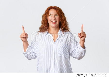 Wondered and amazed, upbeat middle-aged woman react to wonderful news, pointing and looking up with excited smile, reading banner, react to awesome promo offer, standing white background Wondered and amazed, upbeat middle-aged woman react to wonderful news, pointing and looking up with excited smile, reading banner, react to awesome promo offer, standing white background 85436983