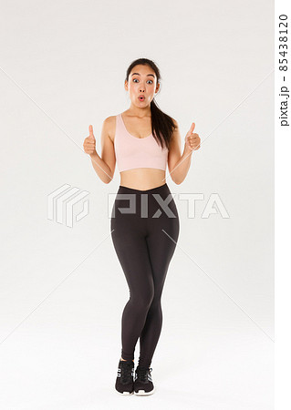 Full length of amazed and impressed female athlete in activewear, showing thumbs-up in approval and looking wondered, praise great workout program, fitness training app or gym membership prices Full length of amazed and impressed female athlete in activewear, showing thumbs-up in approval and looking wondered, praise great workout program, fitness training app or gym membership prices 85438120