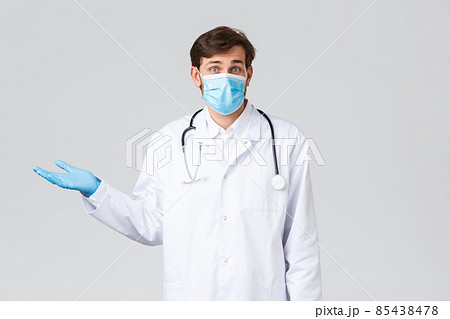 Hospital, healthcare workers, covid-19 treatment concept. Confused and clueless doctor in medical mask, gloves and scrubs, shrugging, spread hands sideways and look puzzled camera, feel unsure Hospital, healthcare workers, covid-19 treatment concept. Confused and clueless doctor in medical mask, gloves and scrubs, shrugging, spread hands sideways and look puzzled camera, feel unsure 85438478