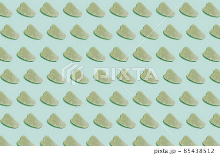 Pattern made with jade gua sha facial tool on pastel green background. Facial massage kit for lifting massage therapy made from natural stones, personal skin care anti-aging tools. 85438512