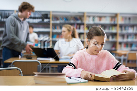 Young girl doing homework in library Young girl doing homework in library 85442859