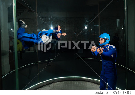 A man teaches a boy to fly in a wind tunnel. 85443389