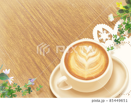 木目のテーブルに乗ったハートのカフェラテアートと花のフレーム 85449651