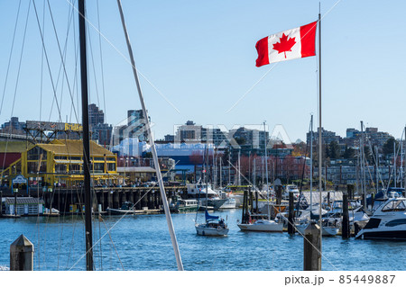 BC, Canada - April 4 2021 : National Flag of Canada and Vancouver marina. Granville Island Public Market. Concept of canadian urban city life. BC, Canada - April 4 2021 : National Flag of Canada and Vancouver marina. Granville Island Public Market. Concept of canadian urban city life. 85449887