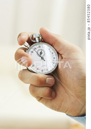 hand holding a silver stop-watch hand holding a silver stop-watch 85452380