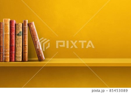 Row of old books on yellow shelf. Horizontal background Row of old books on yellow shelf. Horizontal background 85453089