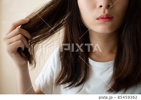 Young woman worried about dry hair, damaged hair and split ends. Hair problems and hair care concept. Young woman worried about dry hair, damaged hair and split ends. Hair problems and hair care concept. 85459362