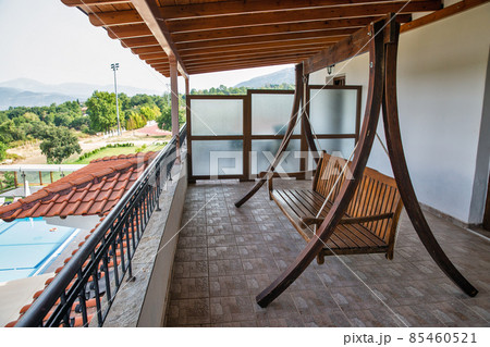 Wooden hanging bench for relaxation on the house balcony Wooden hanging bench for relaxation on the house balcony 85460521