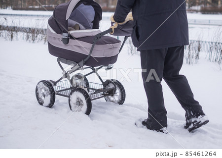 Baby stroller wheel on snowy road in winter. Baby stroller wheel on snowy road in winter. 85461264