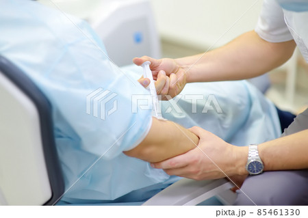 Anesthesiologist injects anesthesia into the patient's vein during dental surgery. Anesthetized patient in the operating room. Installation of dental implants in the clinic. 85461330