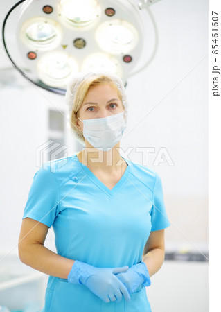 Portrait of female surgeon wearing in medical face mask and protective gloves. Doctor is preparing for surgery in operation room. Portrait of female surgeon wearing in medical face mask and protective gloves. Doctor is preparing for surgery in operation room. 85461607