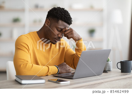 Tired african american manager working on laptop, touching head 85462499