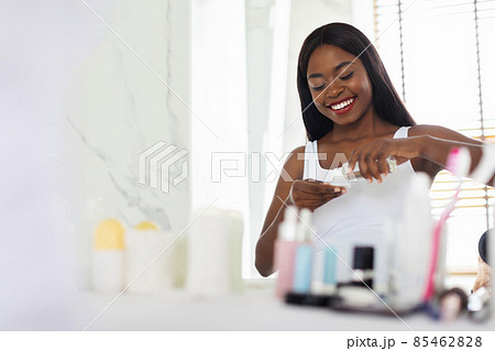 Skin Cleansing. Black Woman Pouring Micellar Water On Cotton Pad In Bathroom Skin Cleansing. Black Woman Pouring Micellar Water On Cotton Pad In Bathroom 85462828
