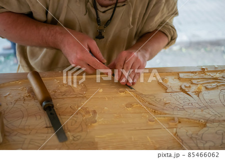 Carpenter carving wood with chisel at medival festival - close up 85466062