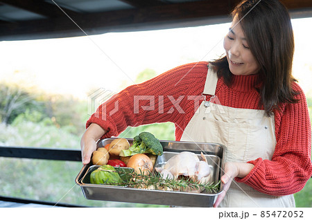 農家でとれた野菜と鳥をみせている生産者のアジア人（日本人）女性に見える写真　帽子つき　カメラ目線	 85472052