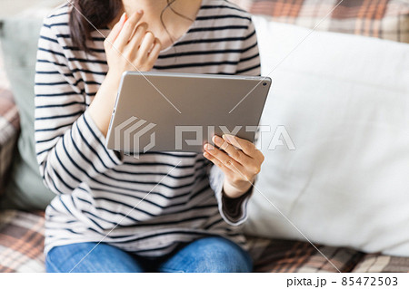 リビングルームでタブレットPCを見る女性 リビングルームでタブレットPCを見る女性 85472503
