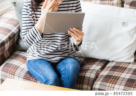 リビングルームでタブレットPCを見る女性 85472505