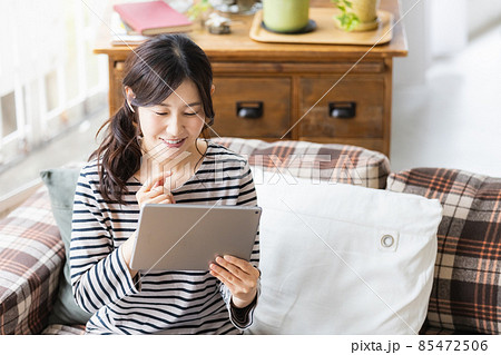 リビングルームでタブレットPCを見る女性 リビングルームでタブレットPCを見る女性 85472506