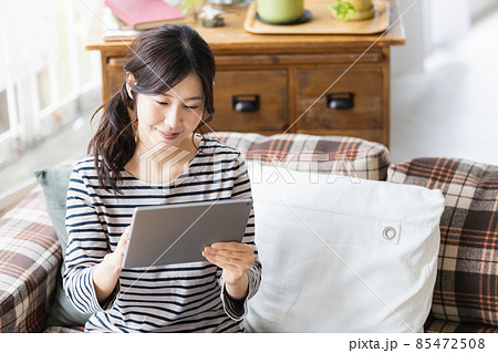 リビングルームでタブレットPCを見る女性 リビングルームでタブレットPCを見る女性 85472508