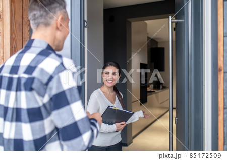 Woman realtor standing near open door inviting man 85472509