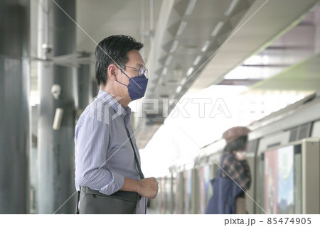 Man commuter with face mask on standing on the subway platform waiting to go inside train. Masked transit concept. Man commuter with face mask on standing on the subway platform waiting to go inside train. Masked transit concept. 85474905
