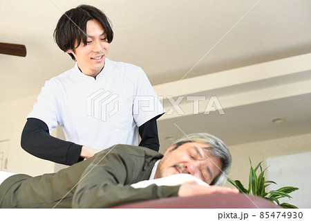 若い整体師の男性とマッサージを受けるシニア男性 85474930