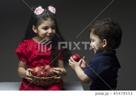 Little girl with her brother holding a pomegranates basket 85479553