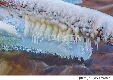 Icicles over the water in the river. Natural landscape. Winter. Background image. Icicles over the water in the river. Natural landscape. Winter. Background image. 85479807