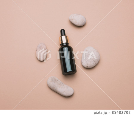 brown glass bottle with a pipette stands on a brown background. Container for cosmetics brown glass bottle with a pipette stands on a brown background. Container for cosmetics 85482702