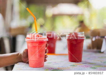 Female hand holding strawberry smoothie drink in plastic cup. 85483937