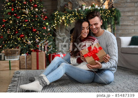 Happy couple with gift box in living room decorated for Christmas Happy couple with gift box in living room decorated for Christmas 85487339