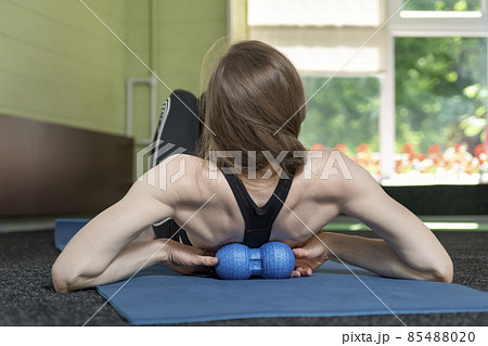 Athletic girl using roller to roll out small of the back muscles. Ball for Myofascial massage. Self-massage. 85488020