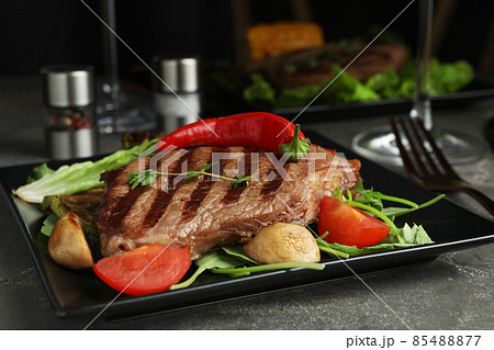 Delicious beef steak served on grey table, closeup Delicious beef steak served on grey table, closeup 85488877