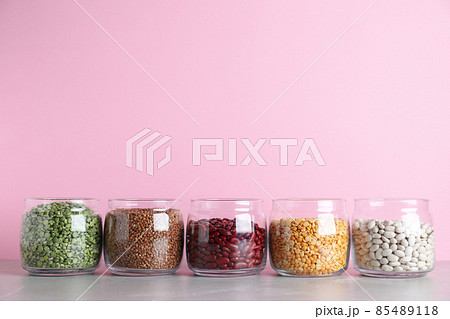 Glass jars with different types of groats on grey marble table Glass jars with different types of groats on grey marble table 85489118