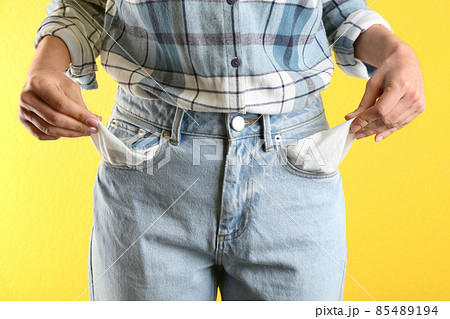 Woman showing empty pockets on yellow background, closeup Woman showing empty pockets on yellow background, closeup 85489194