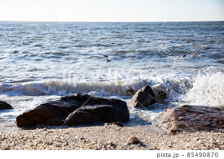 Waves crashing against the rocks from the blue sea beyond the horizon Waves crashing against the rocks from the blue sea beyond the horizon 85490870