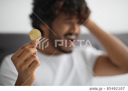 Golden bitcoin in frustrated indian man hands, selective focus 85492107