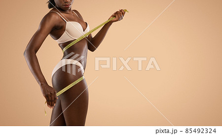 Unrecognizable black woman measuring her athletic body Unrecognizable black woman measuring her athletic body 85492324