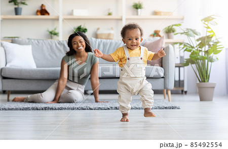 First Steps. Adorable Black Infant Child Walking In Living Room At Home First Steps. Adorable Black Infant Child Walking In Living Room At Home 85492554