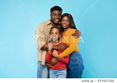 African American man hugging his wife and smiling daughter 85492586