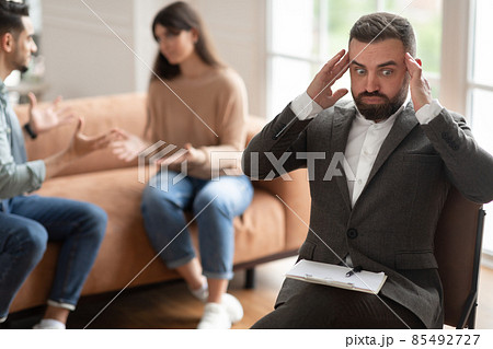 Couple arguing at therapy session, male therapist grabbing head 85492727